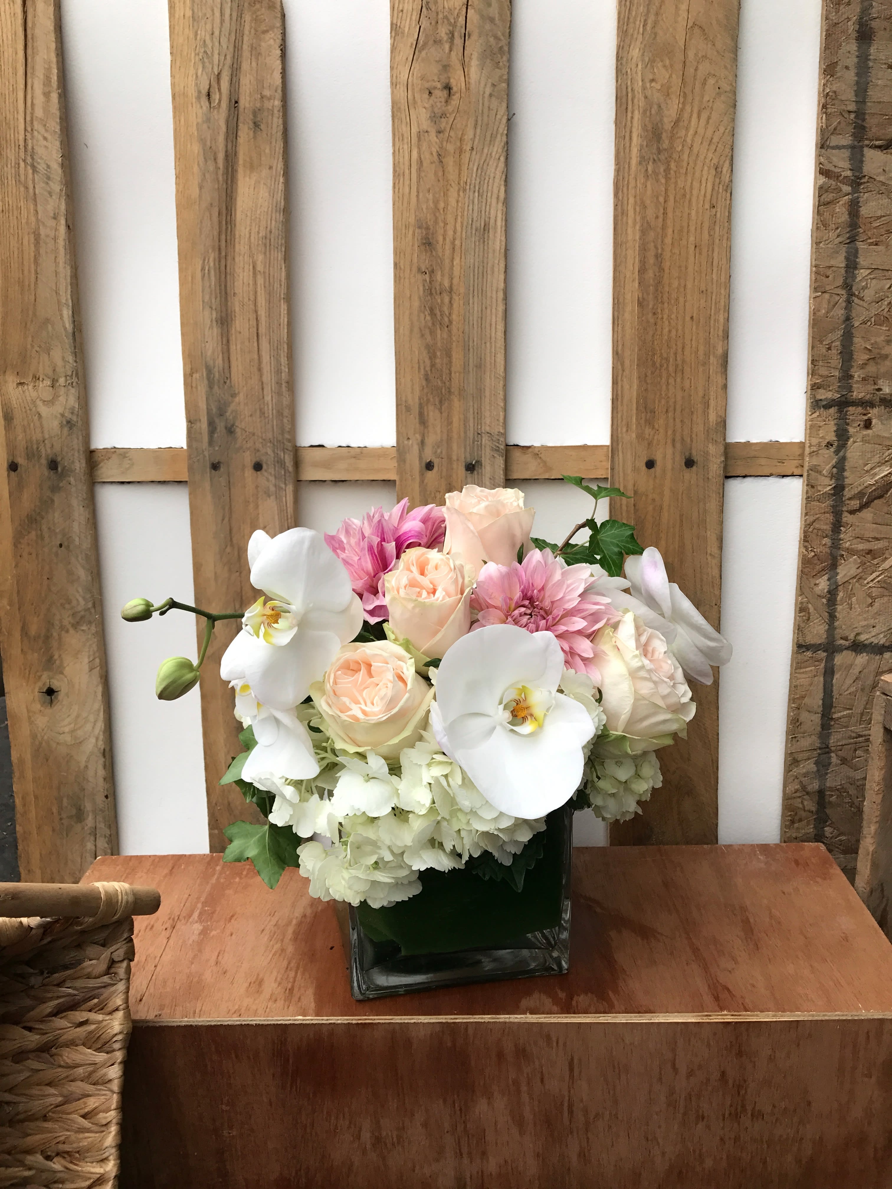 Pink and white floral arrangement in a square glass vase