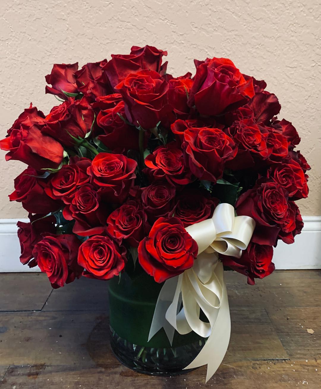 Bouquet of red roses in a glass vase with a white ribbon
