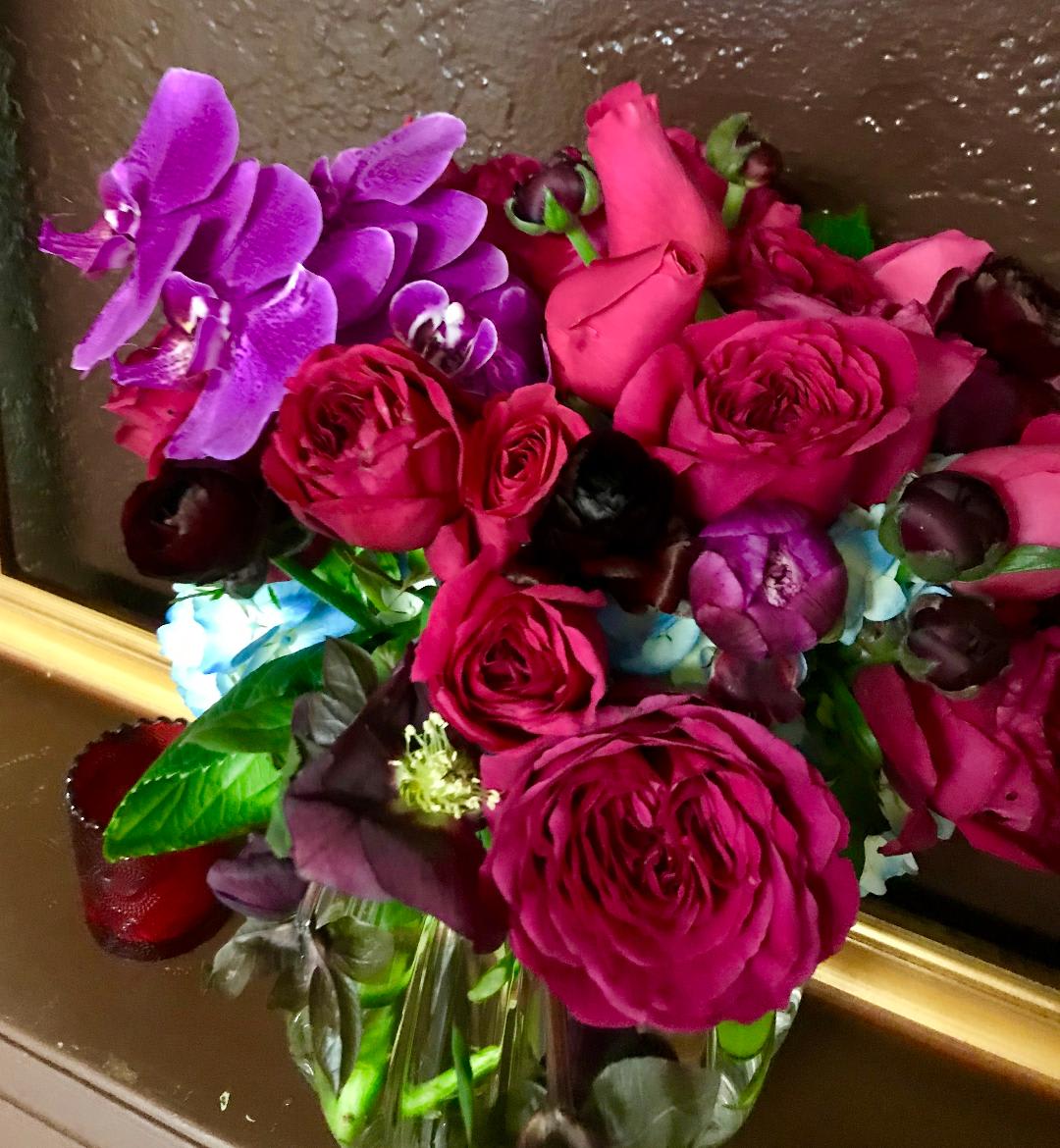 Bouquet of pink roses and purple orchids in a glass vase