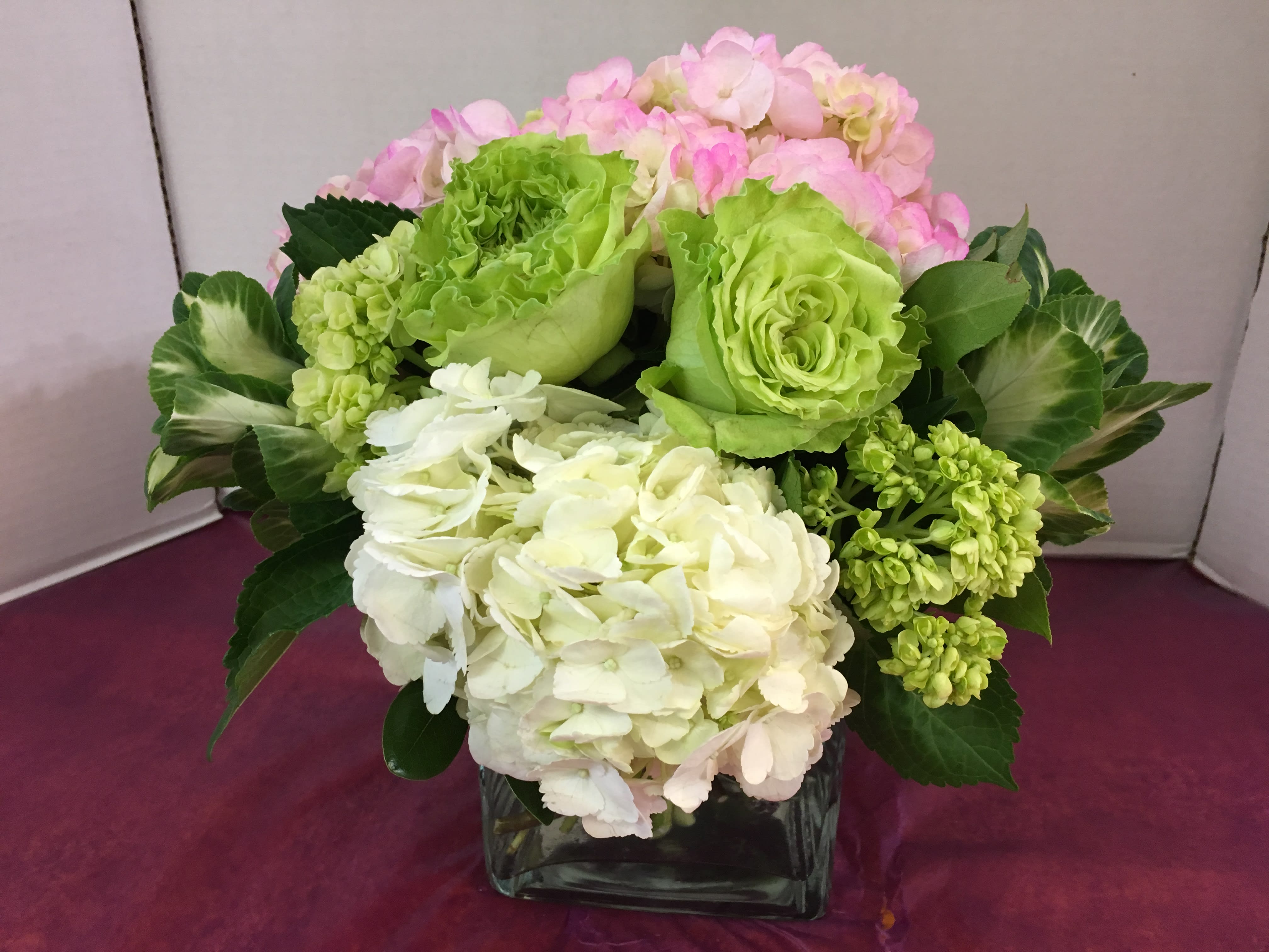 Bouquet of pink, green, and white hydrangeas in a square glass vase