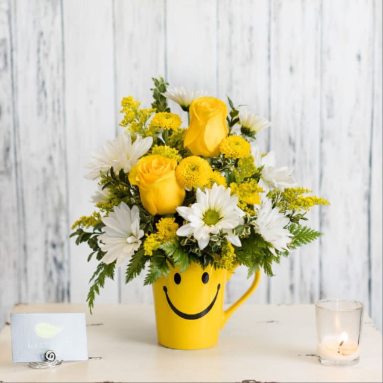 Yellow and white flower arrangement in a smiley-face mug
