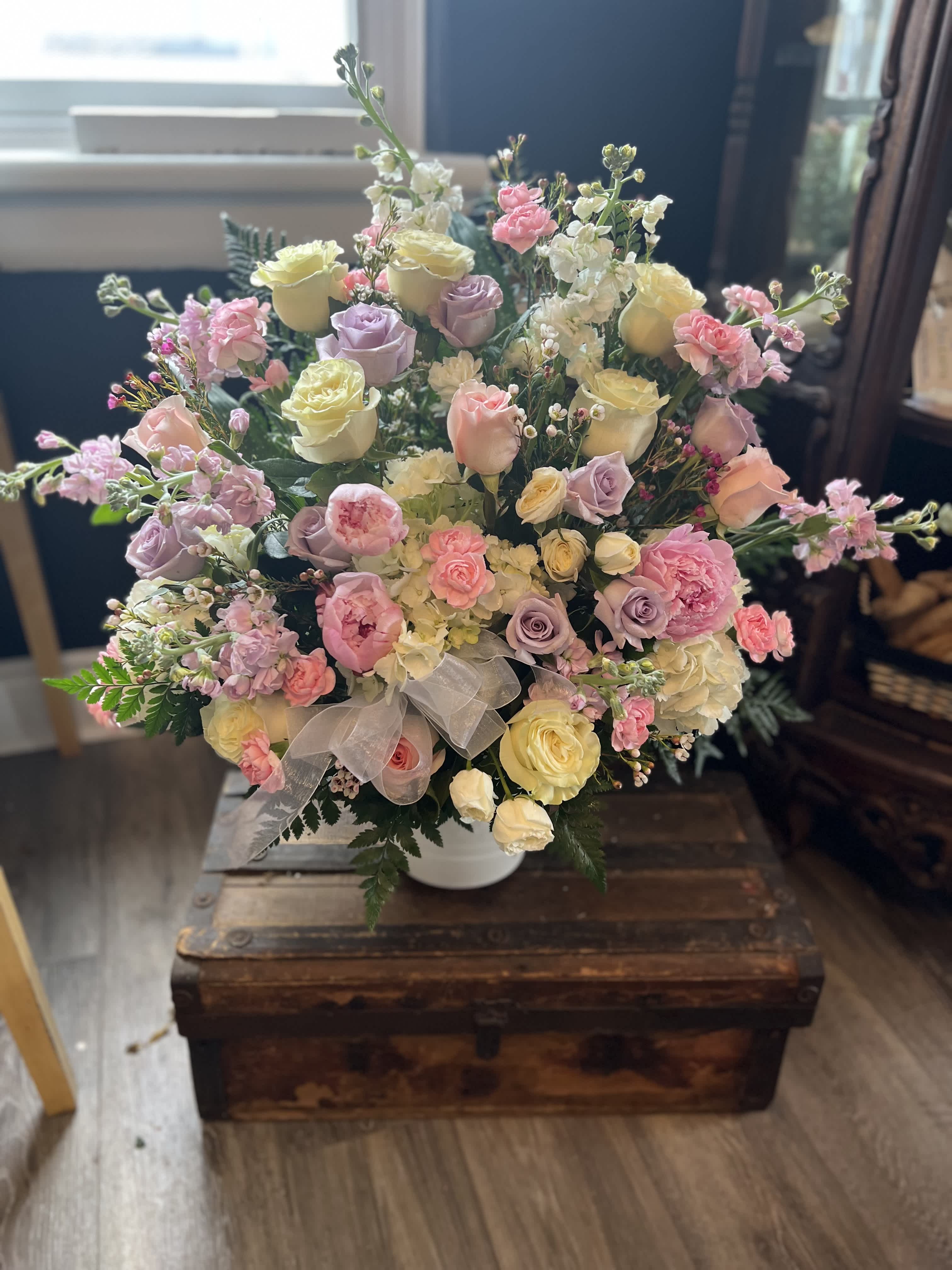 Pastel rose bouquet in a white vase with a sheer ribbon