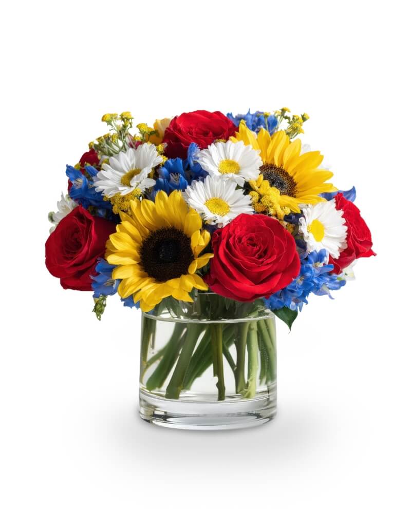 Stars and Sunlight - Celebrate Independence Day with bold, bright beauty. Stars and Sunlight bursts with patriotic spirit, featuring classic red roses, sunny yellow sunflowers, and crisp white daisies surrounded by blue delphinium. It's a cheerful, firework-worthy bouquet designed to make your celebration pop with pride and joy.