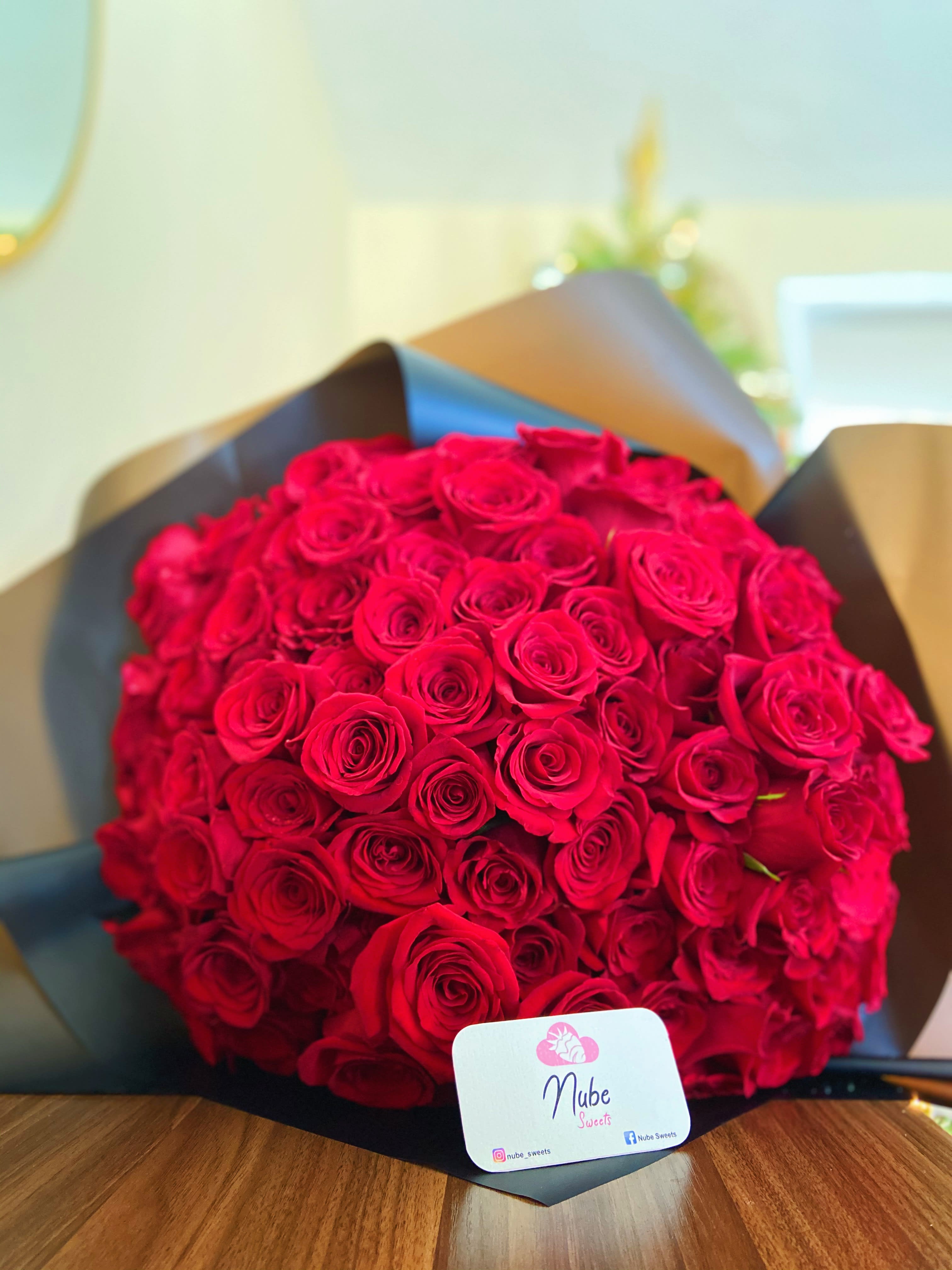 Large bouquet of red roses wrapped in dark paper