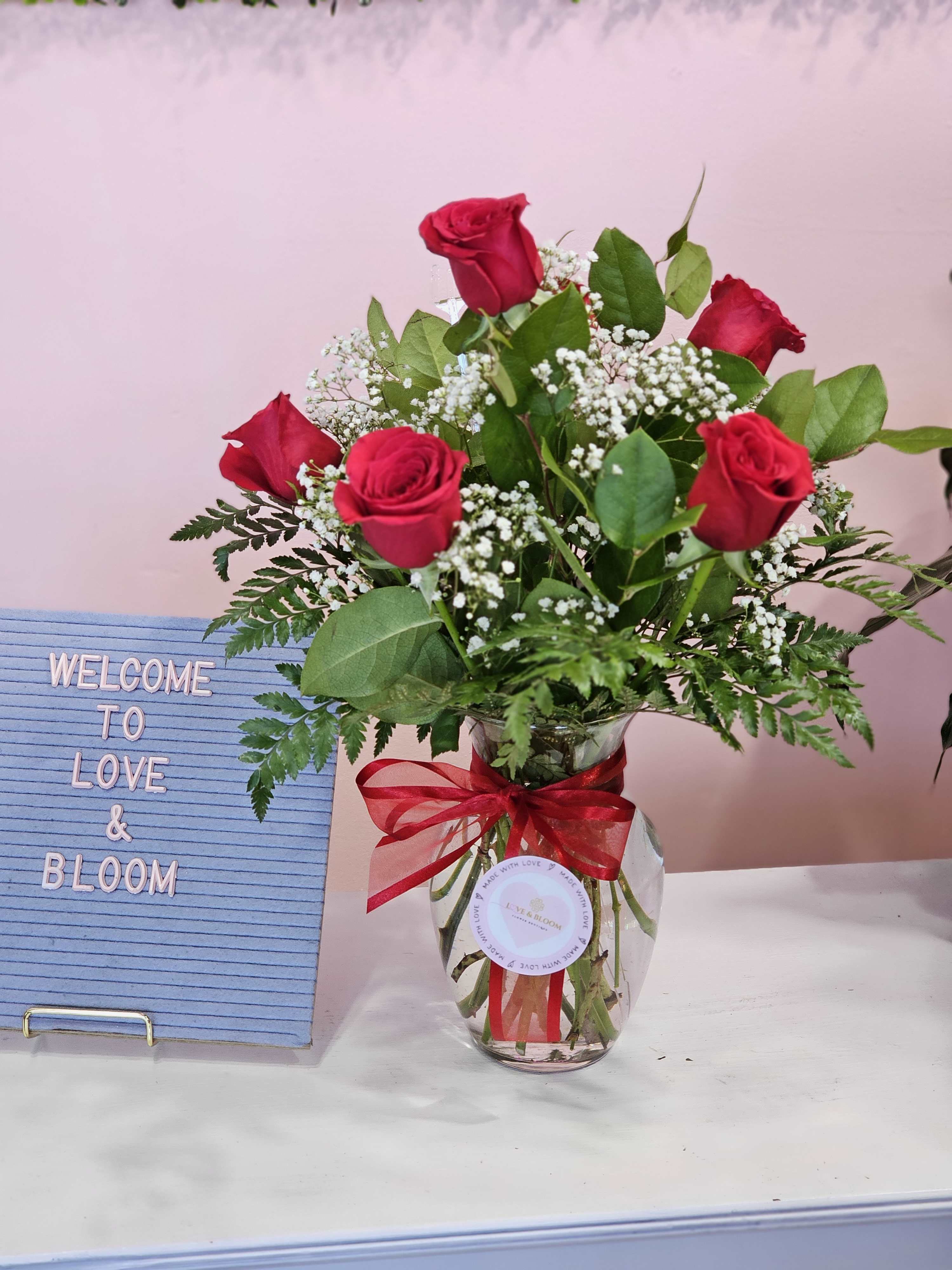 Red roses in a glass vase with a red ribbon