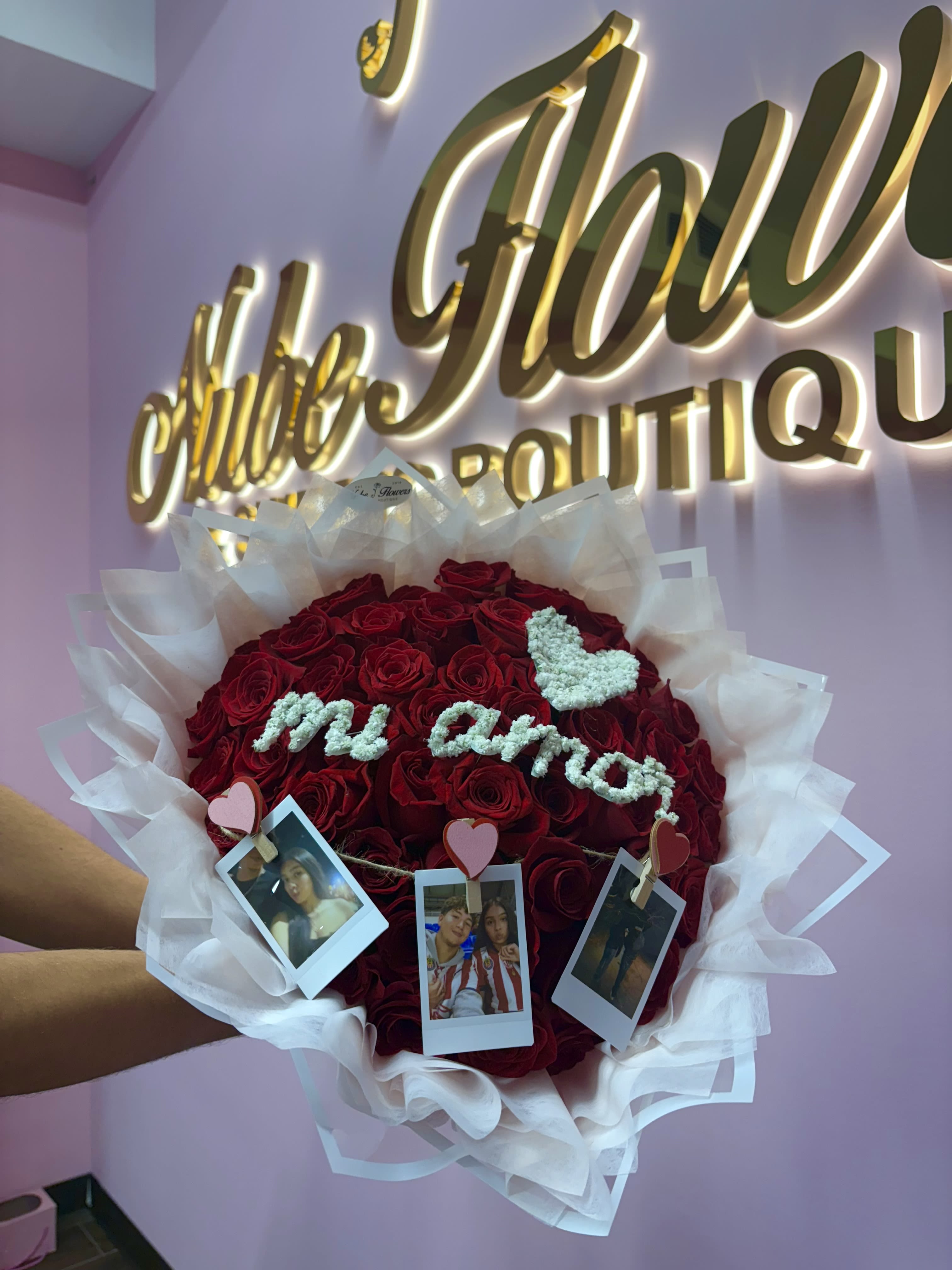 Heart-shaped bouquet of red roses with white wrapping and photo clips