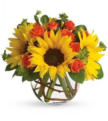 Sunflowers and orange roses arranged in a clear glass vase