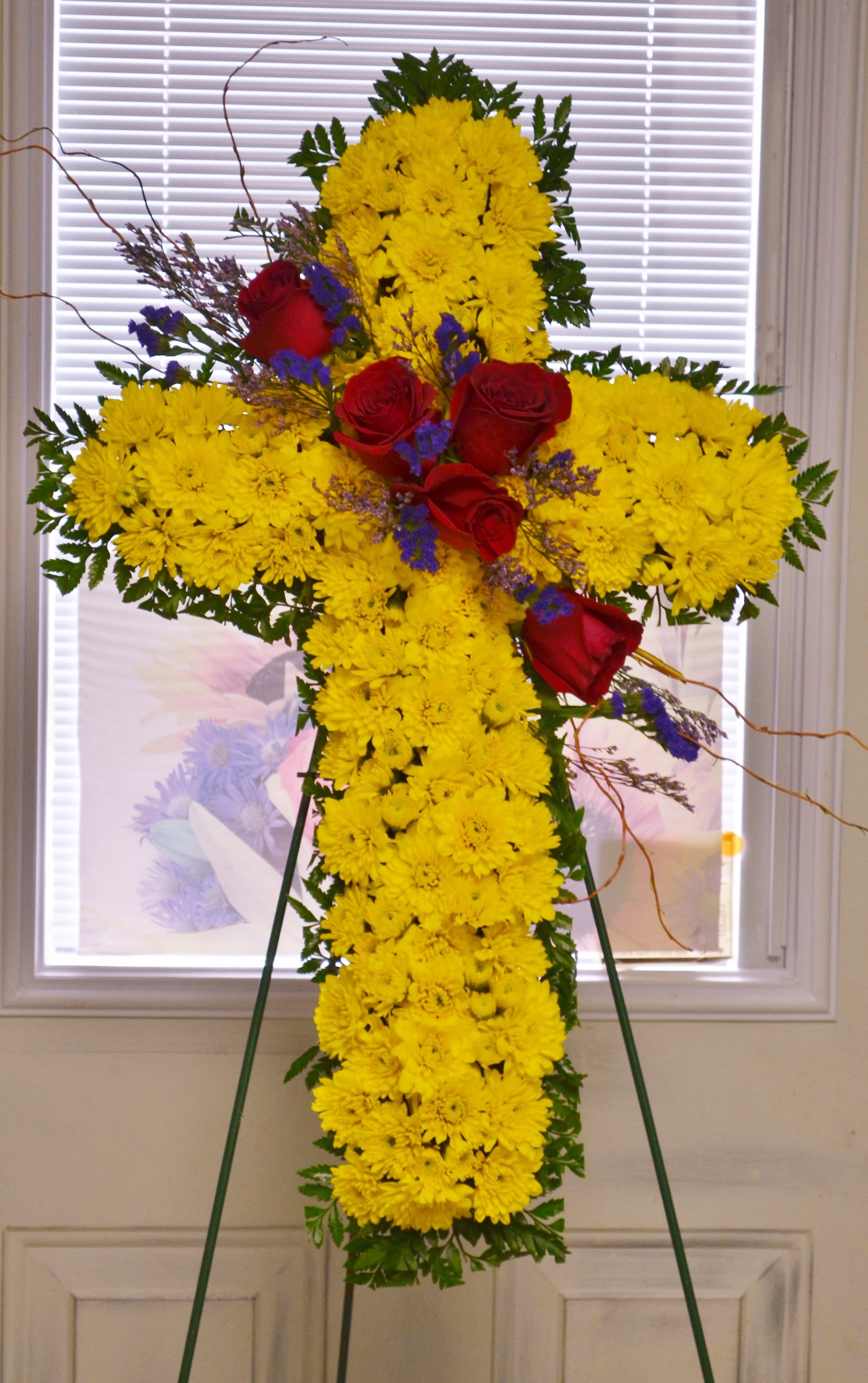 Yellow chrysanthemum cross with red roses on an easel