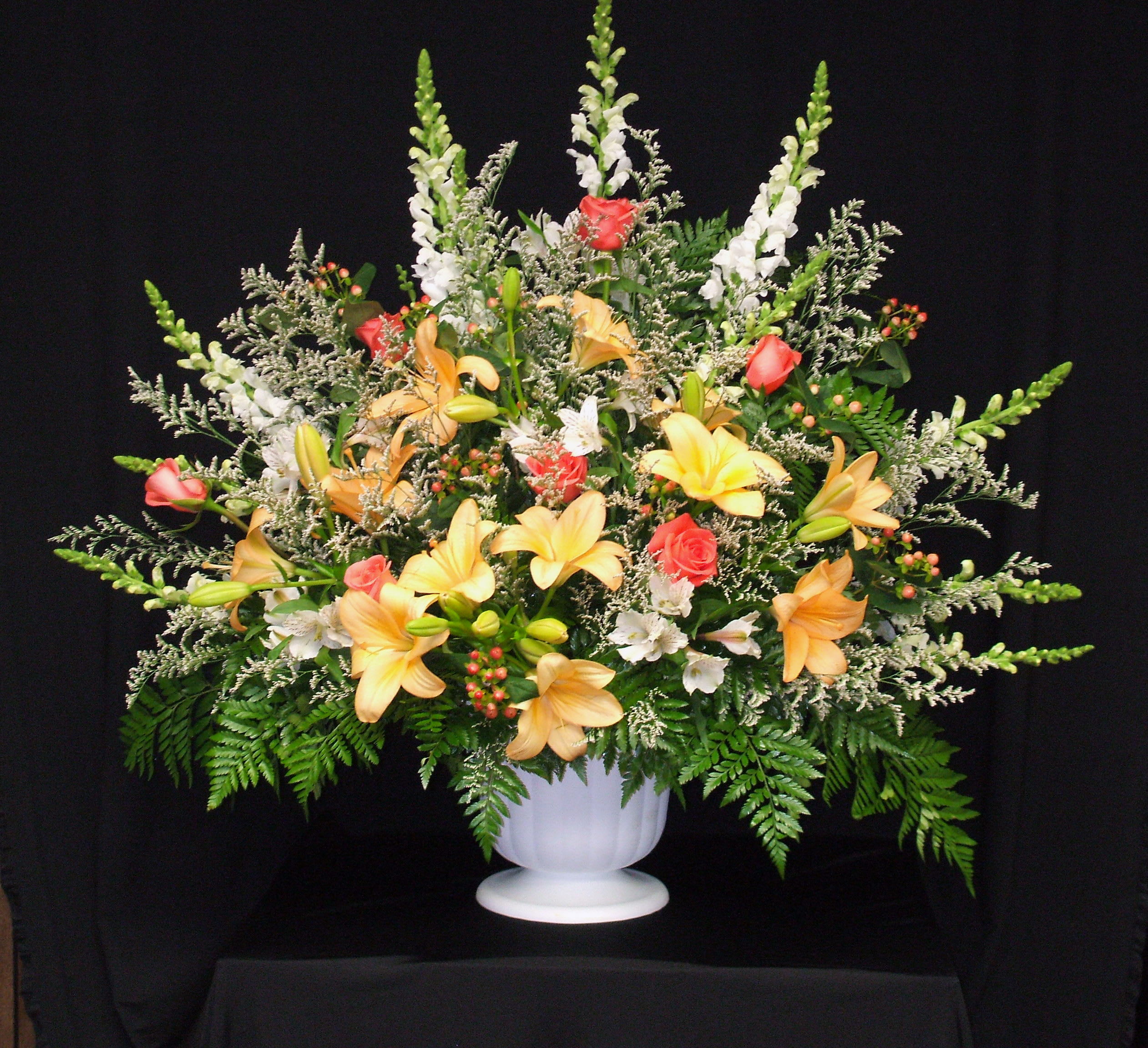 Large floral arrangement in a white urn with lilies and roses