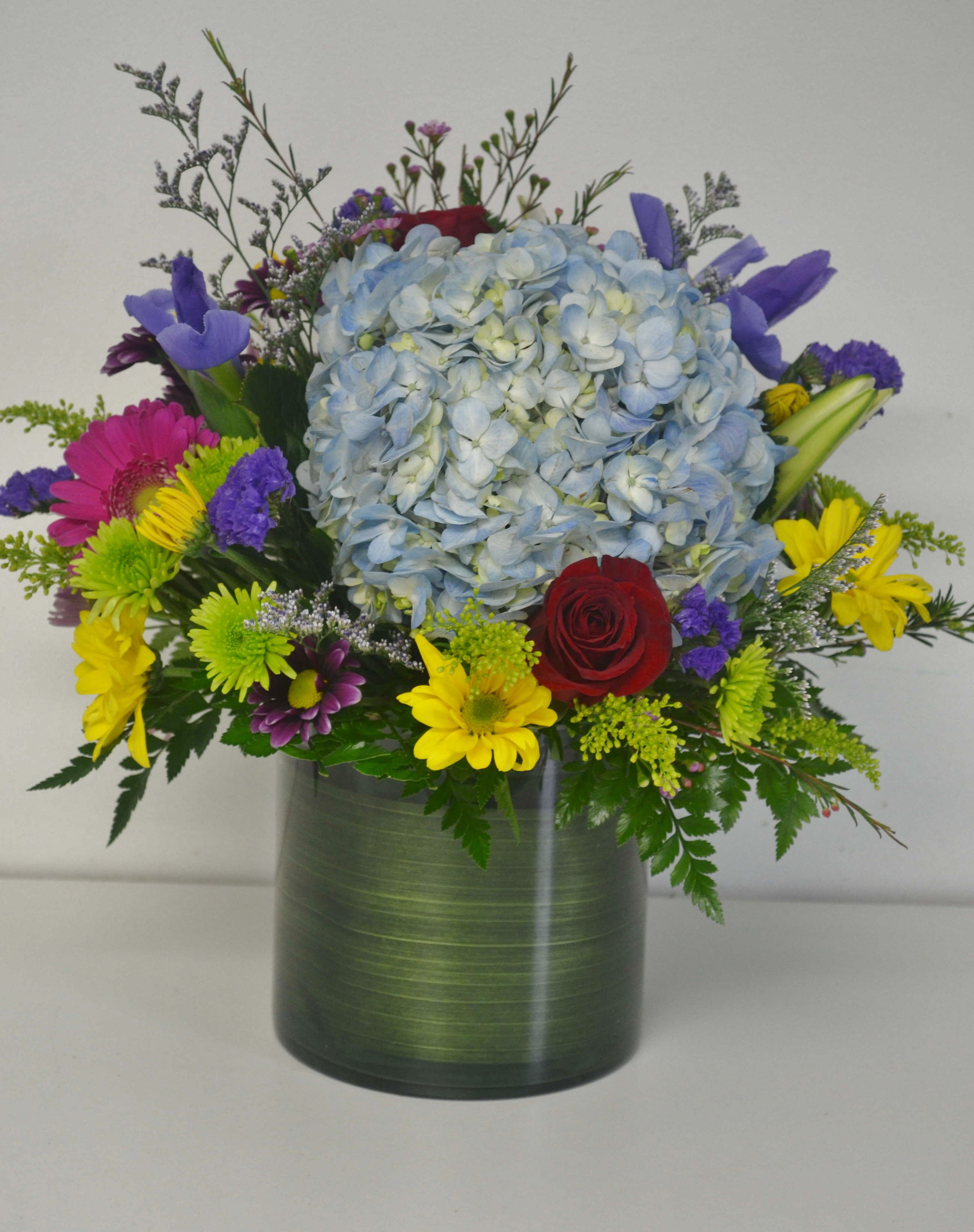 Colorful bouquet with blue hydrangea in a green vase