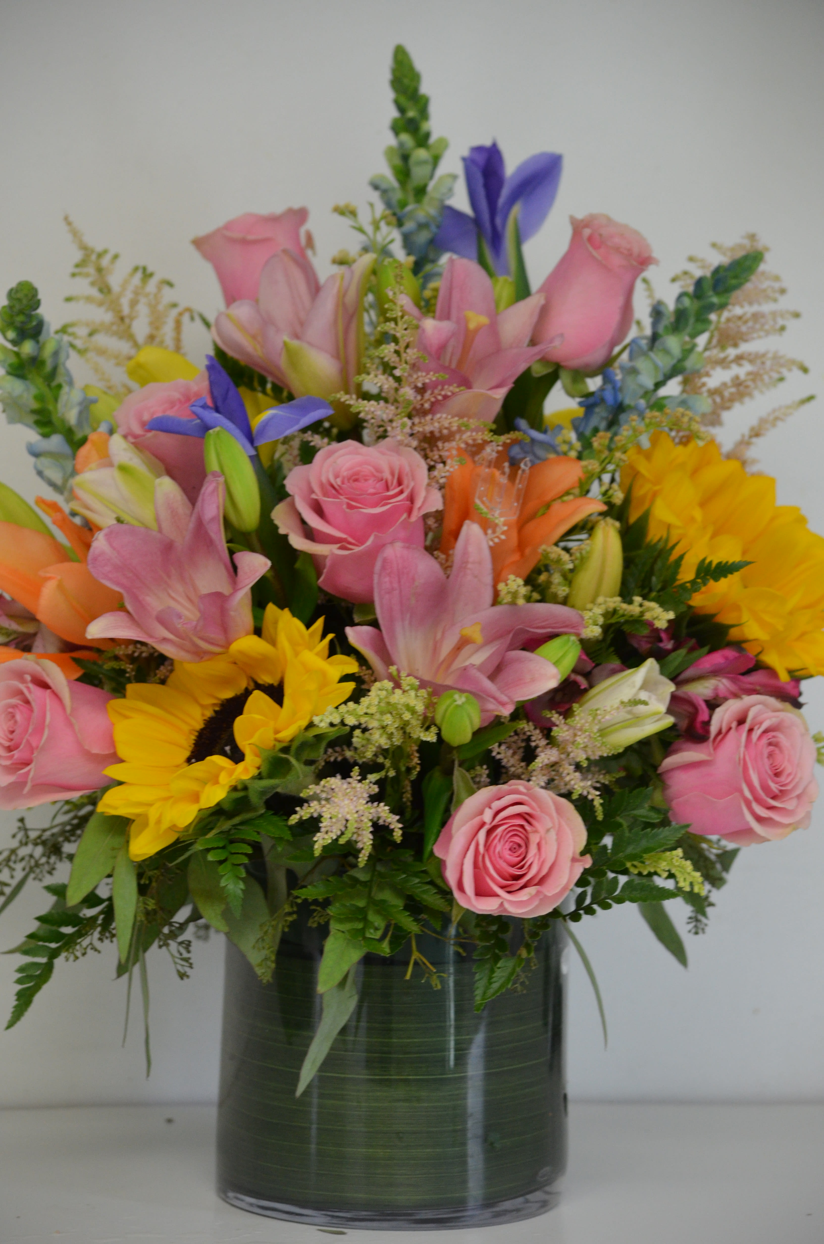 Pink roses, lilies, and sunflowers in a glass vase