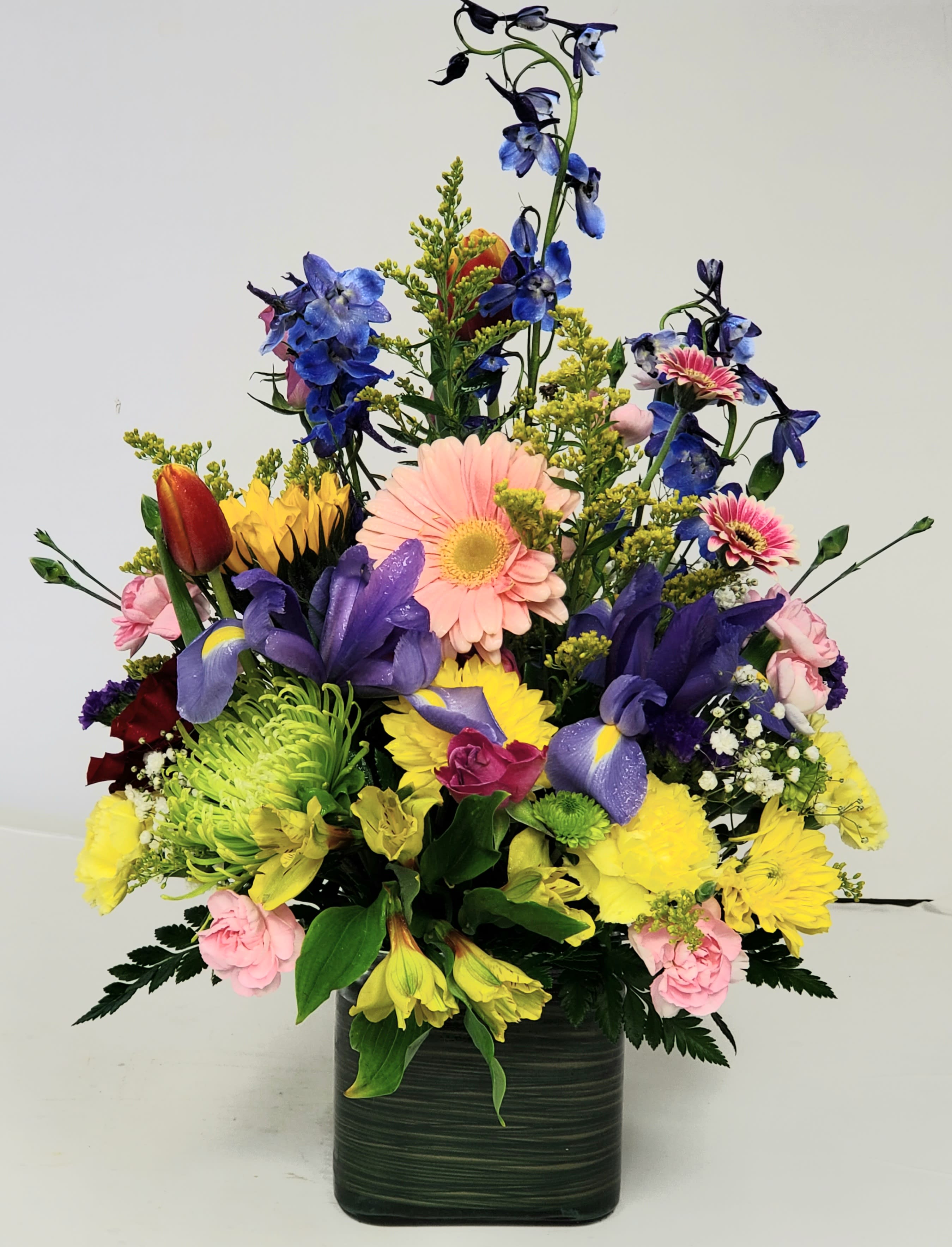 Colorful mixed flower arrangement in a dark green vase