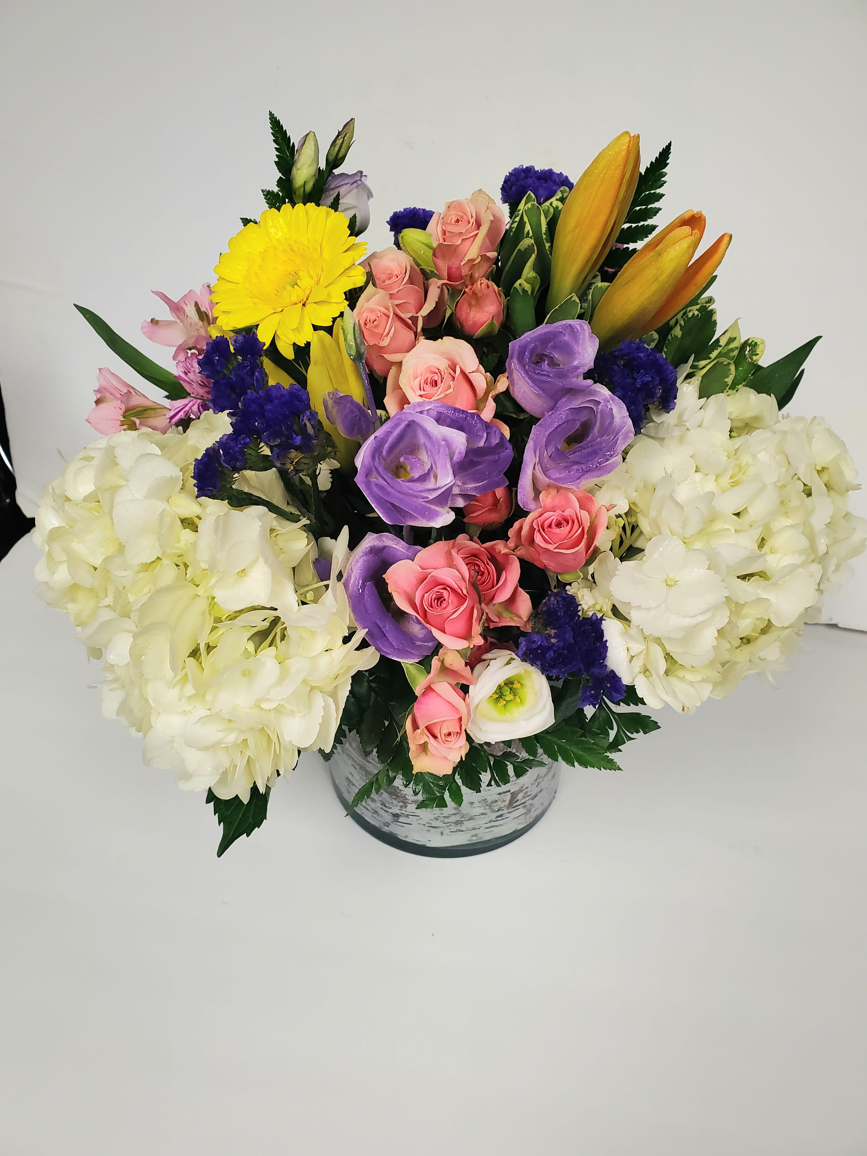 Mixed bouquet in a round vase with pink, purple, yellow, and white flowers