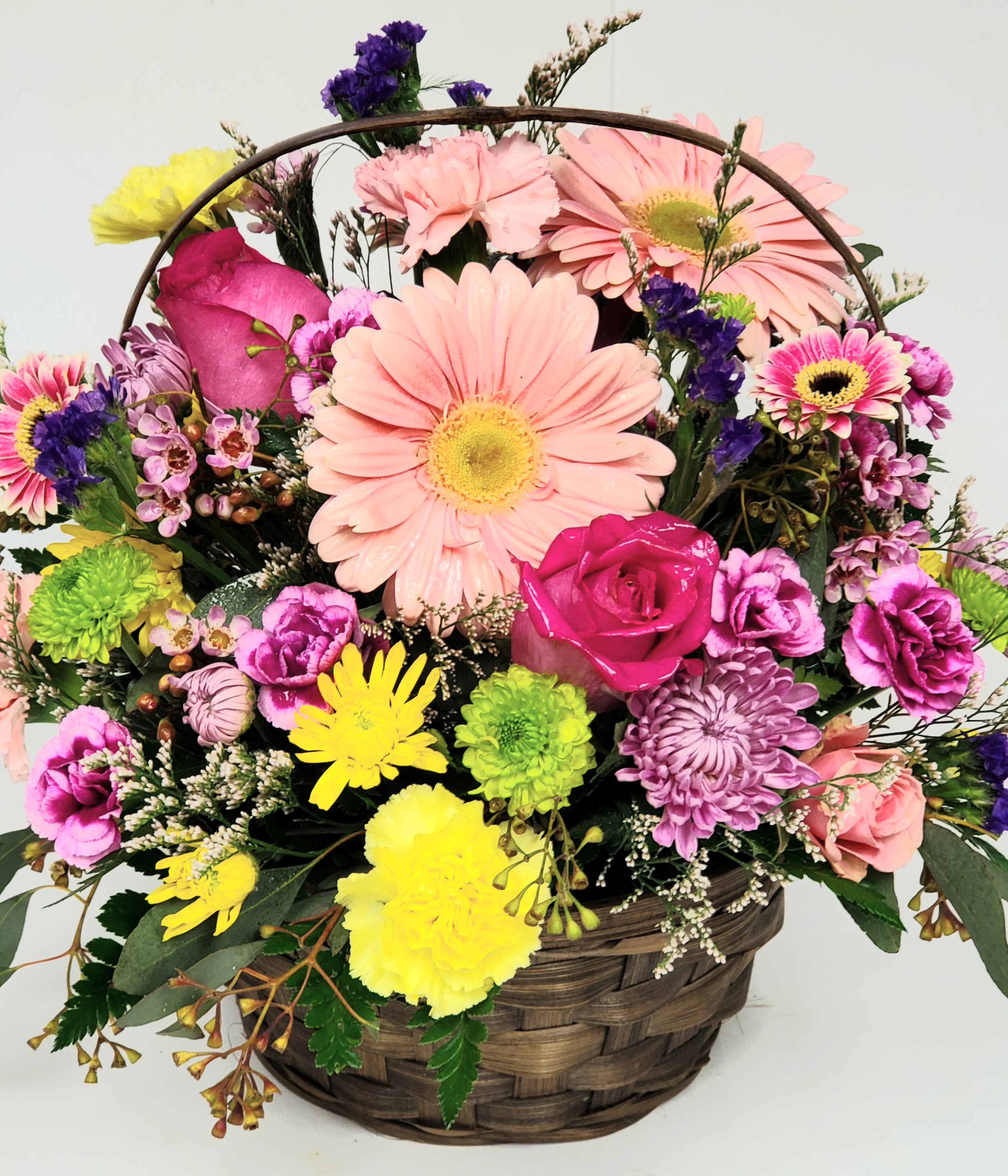 Mixed bouquet in a woven basket with pink daisies and roses