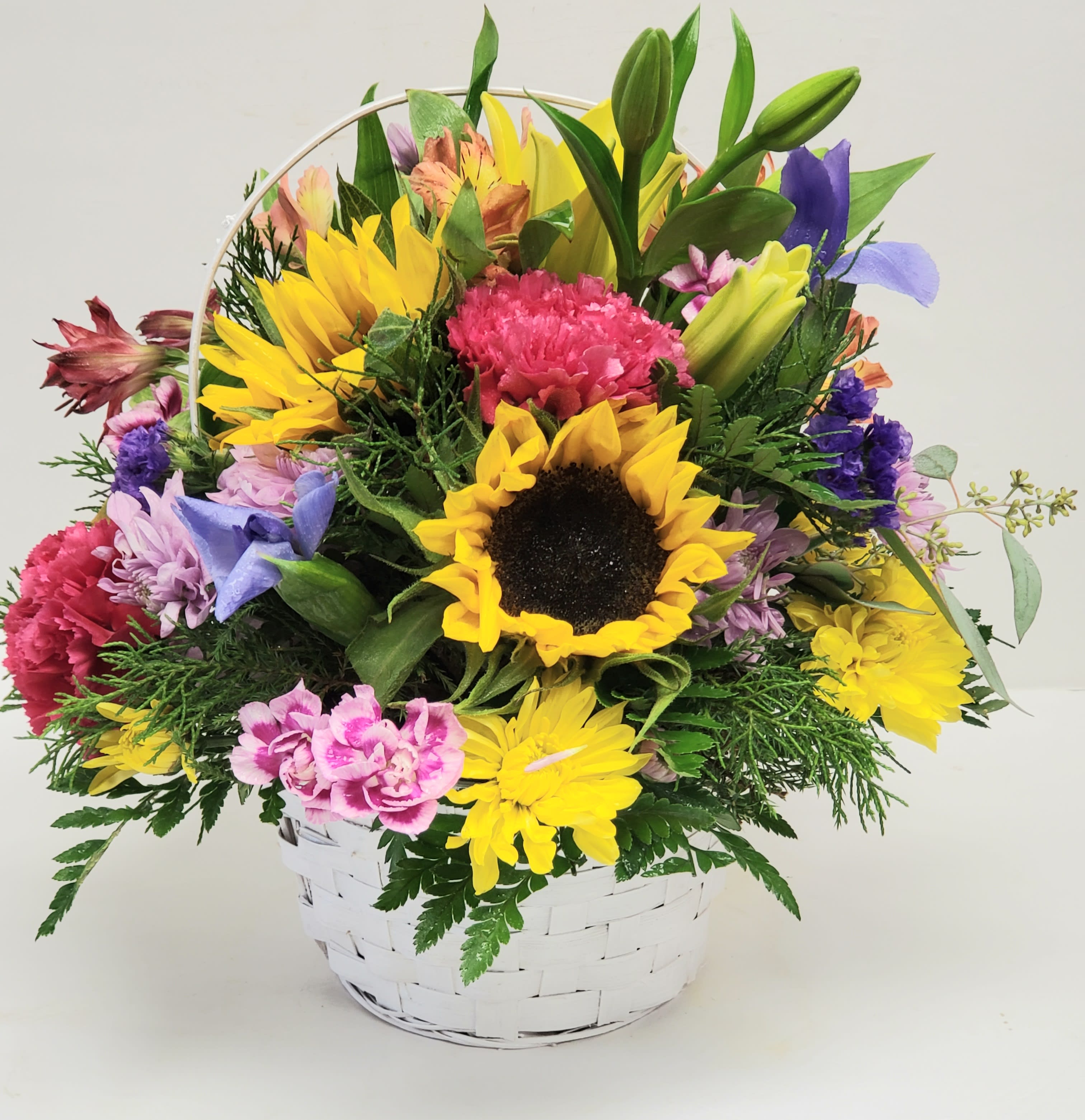 Colorful mixed flower basket with a sunflower and lilies in a white basket