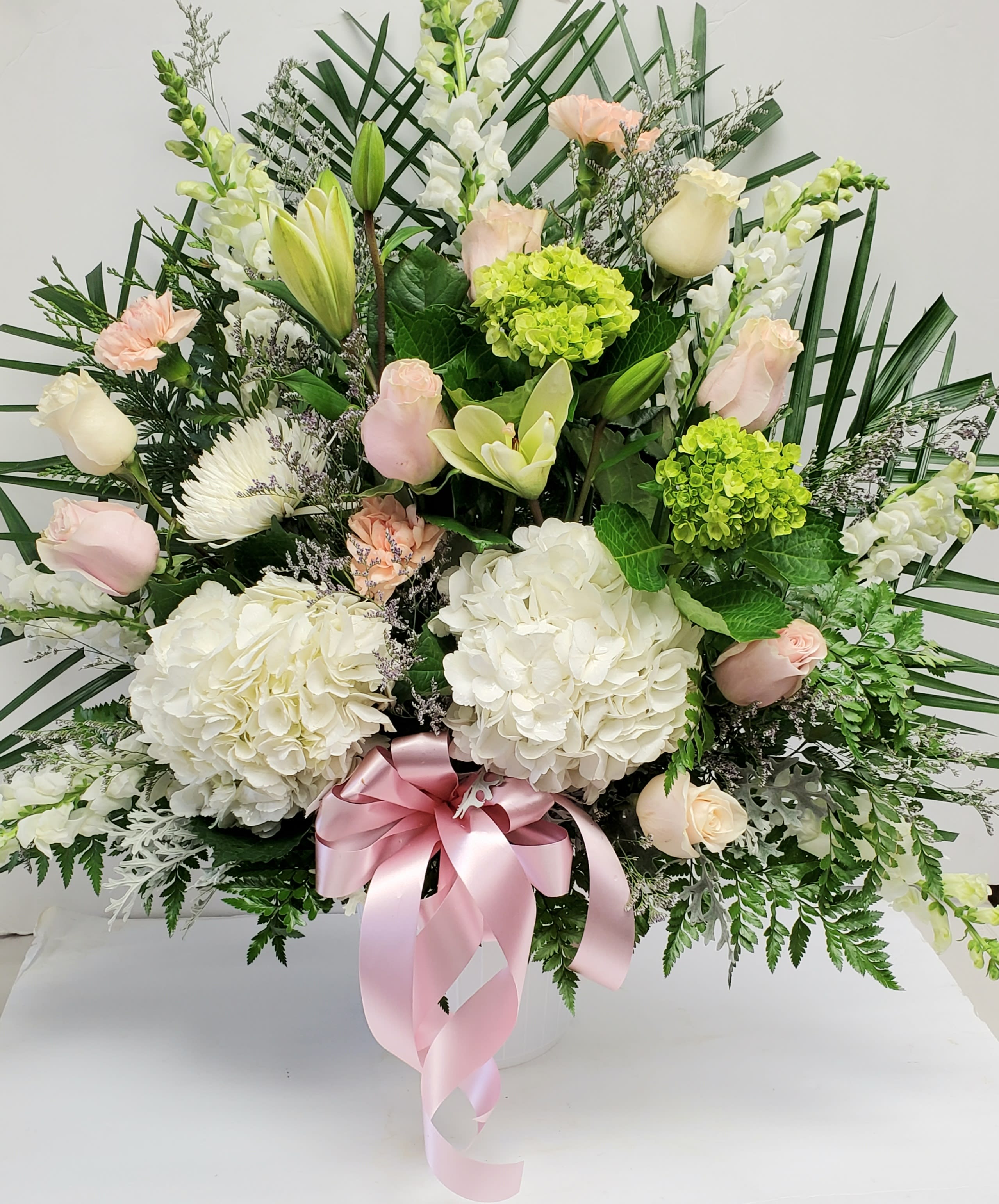 Large floral arrangement with white and pale pink blooms in a white vase