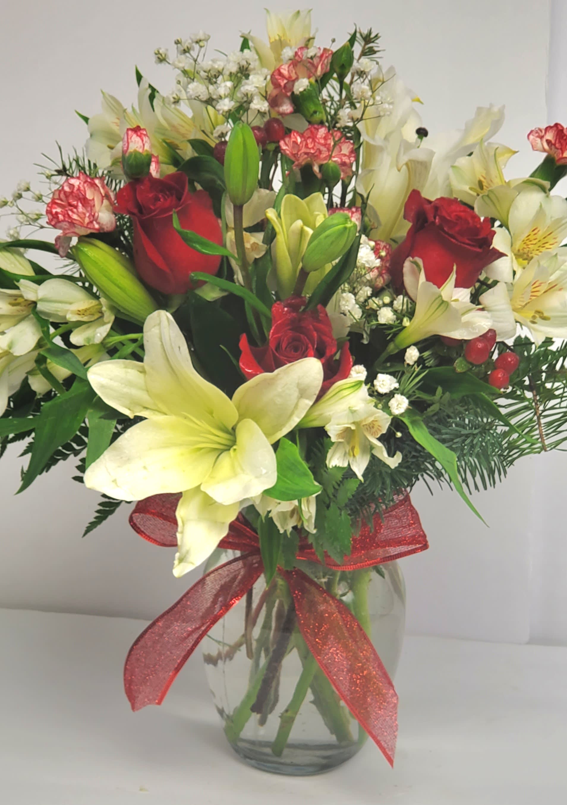 Bouquet of red roses and white lilies in a glass vase with a red ribbon