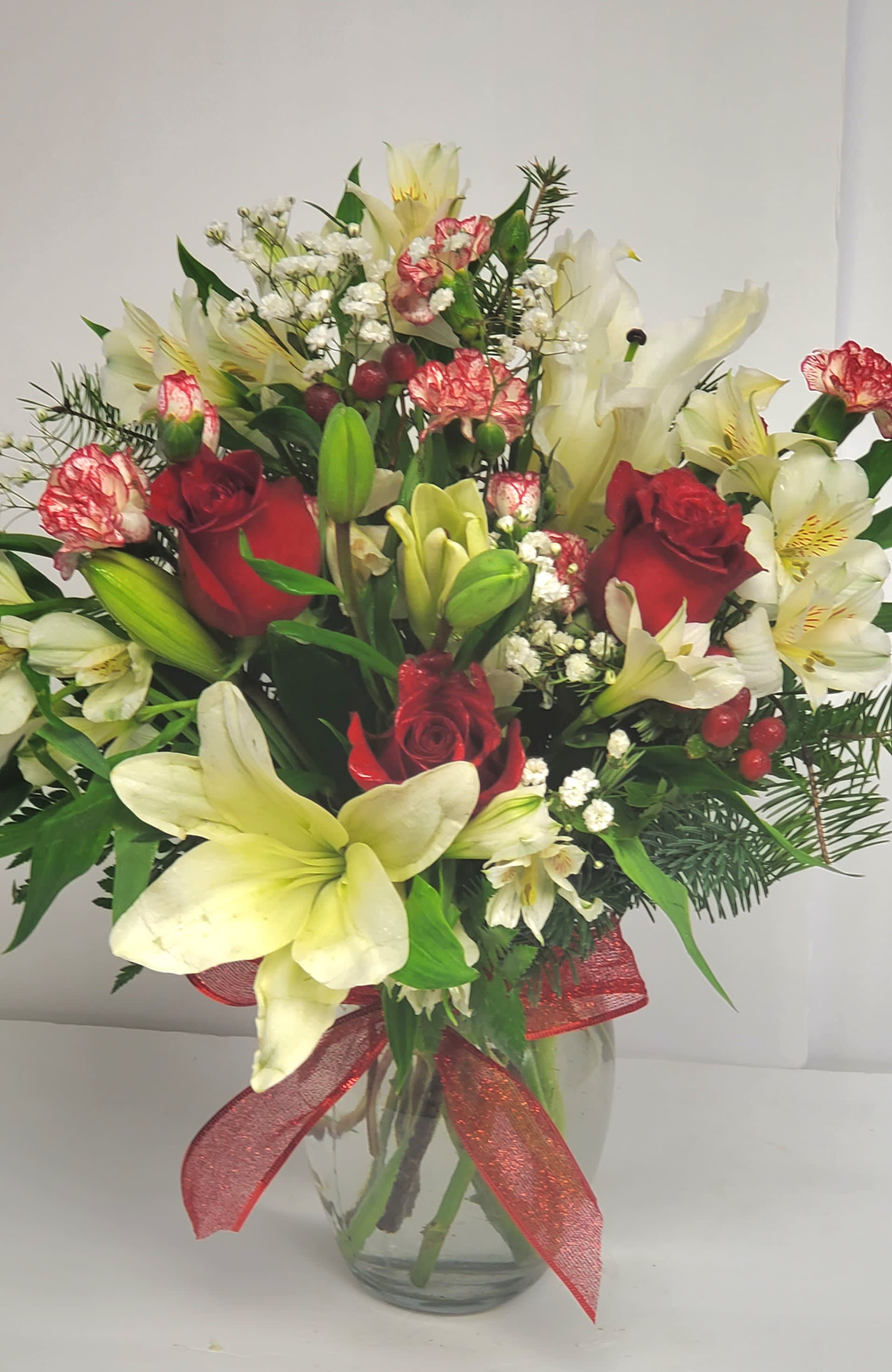 Bouquet of red roses and white lilies in a glass vase with a red ribbon