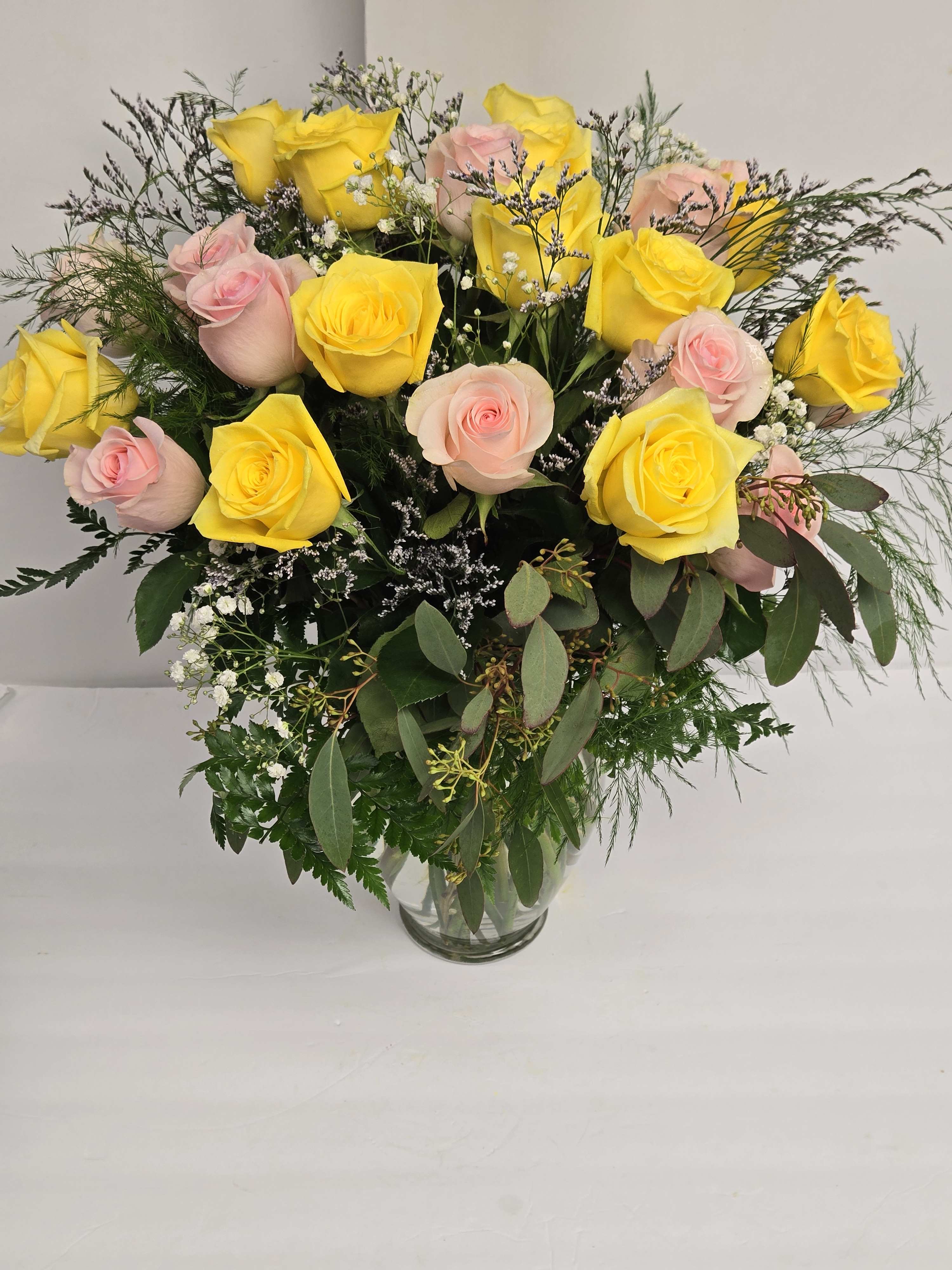 Bouquet of yellow and pale pink roses in a clear glass vase