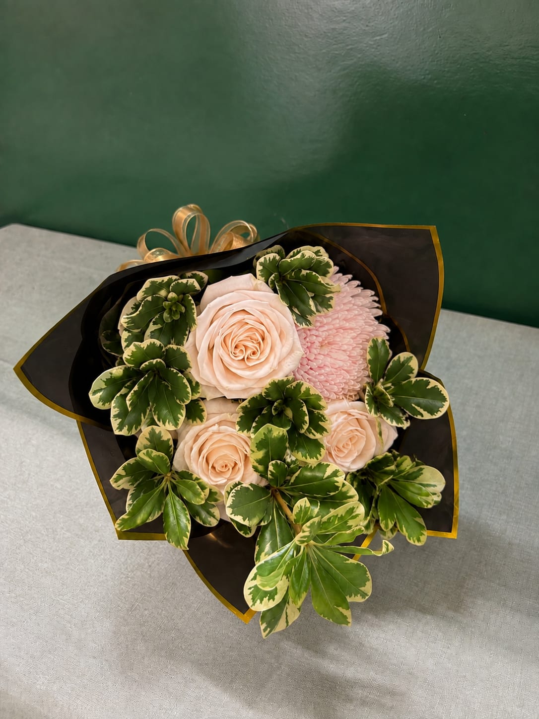 Bouquet of pale pink roses and a pink chrysanthemum with variegated green foliage