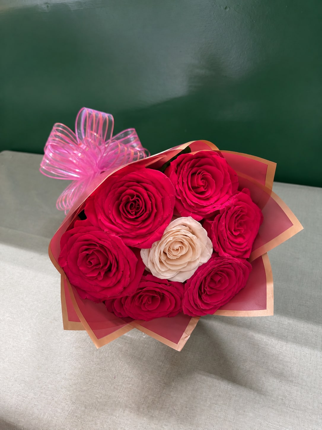 Bouquet of hot pink and cream roses wrapped in pink paper with a ribbon bow
