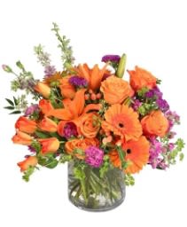 Orange and purple mixed bouquet in a glass vase