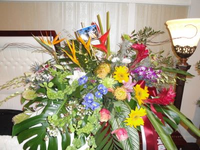 Large tropical flower arrangement with bright mixed blooms and broad leaves