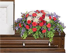 Colorful floral arrangement on a casket with red, white, and purple flowers