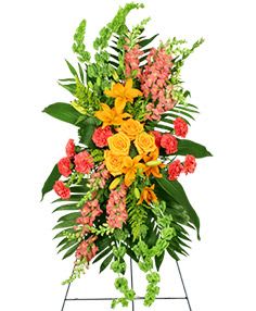 Standing floral spray with yellow roses and pink flowers on a metal easel