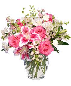 Pink roses and lilies arranged in a clear glass vase