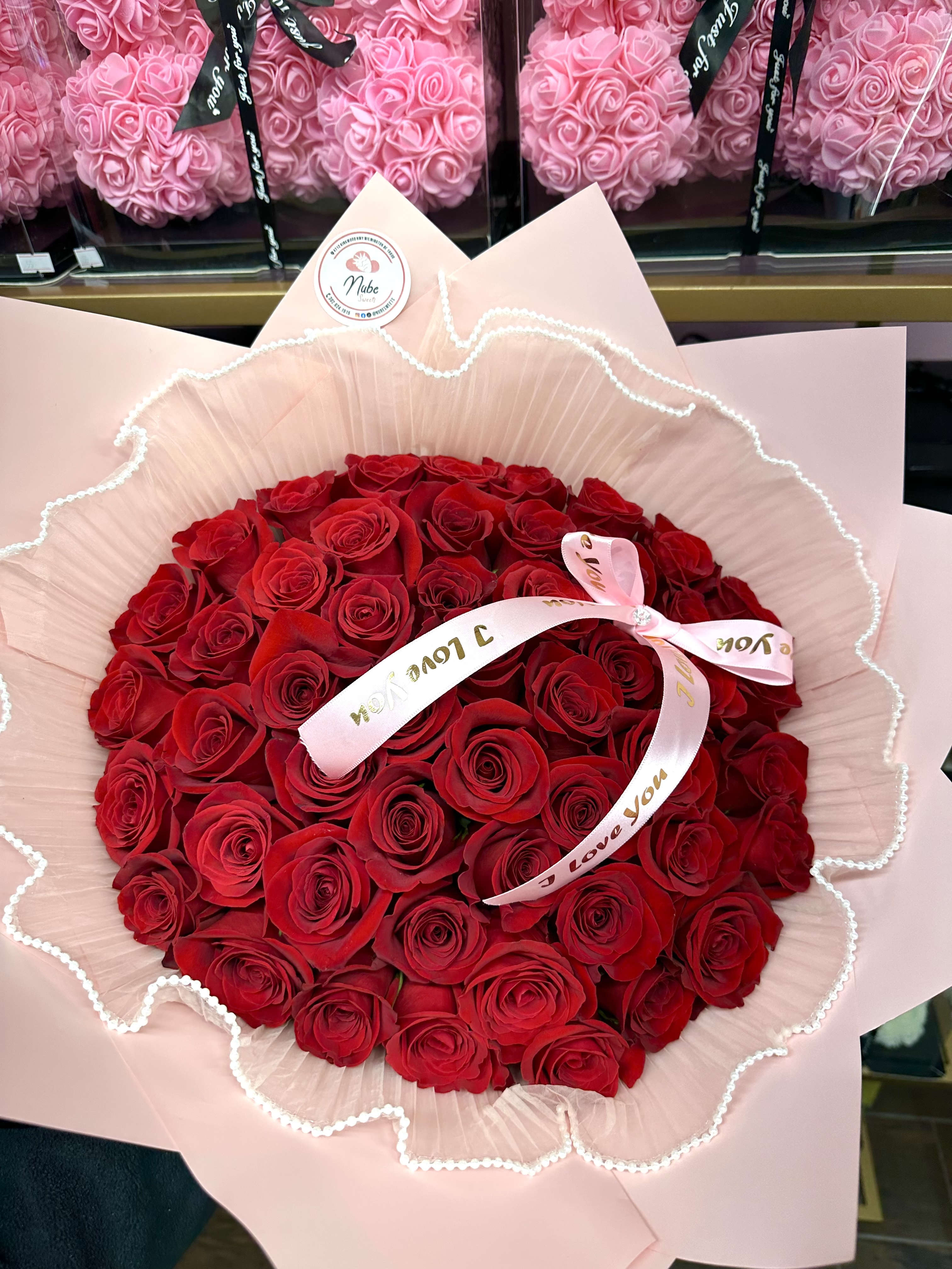 Bouquet of red roses wrapped in pale pink paper with a ribbon