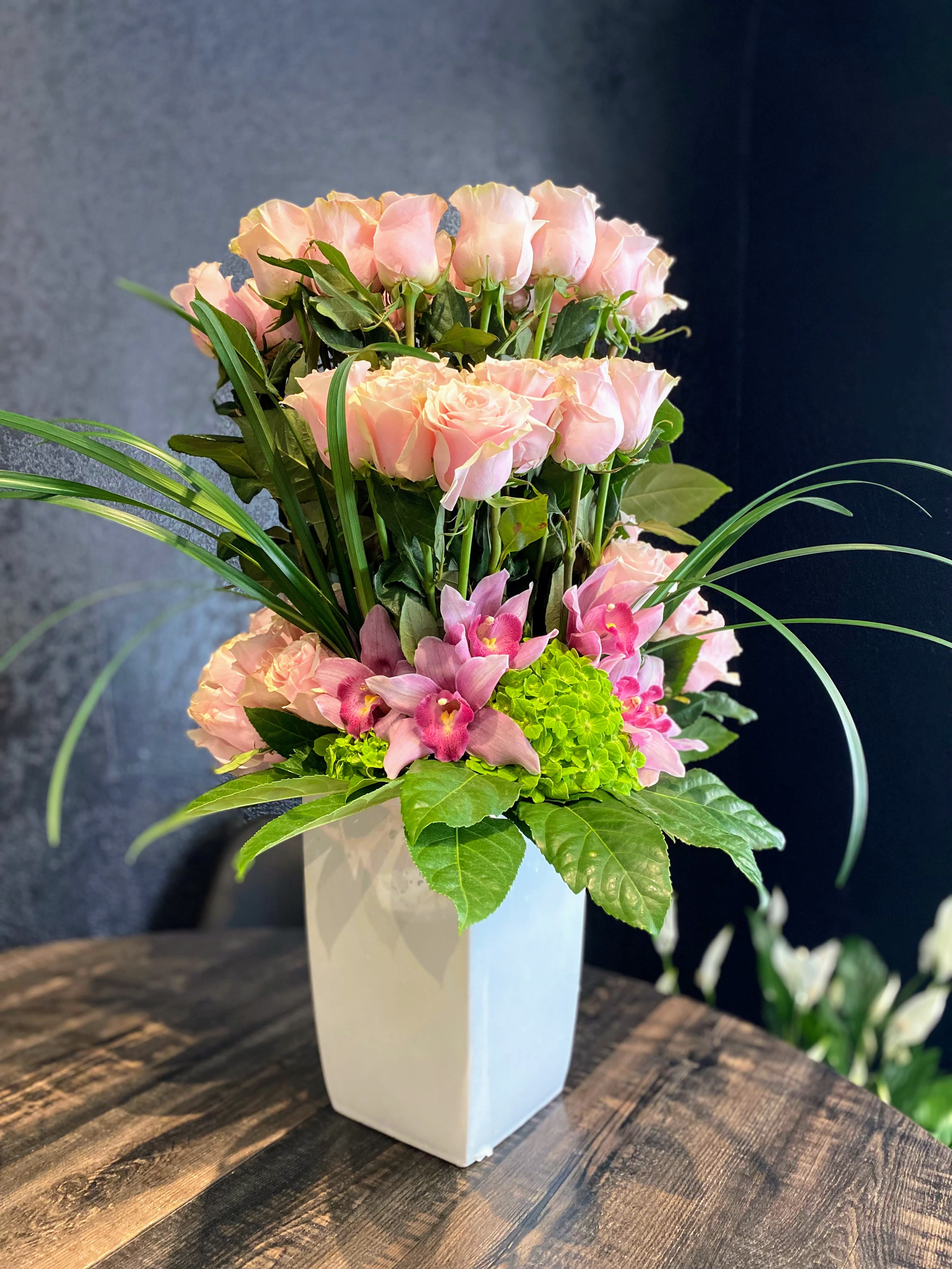 Pink roses and orchids arranged in a white vase
