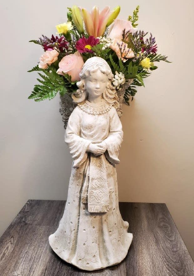 Flower arrangement in a statue vase with pink, yellow, and purple blooms