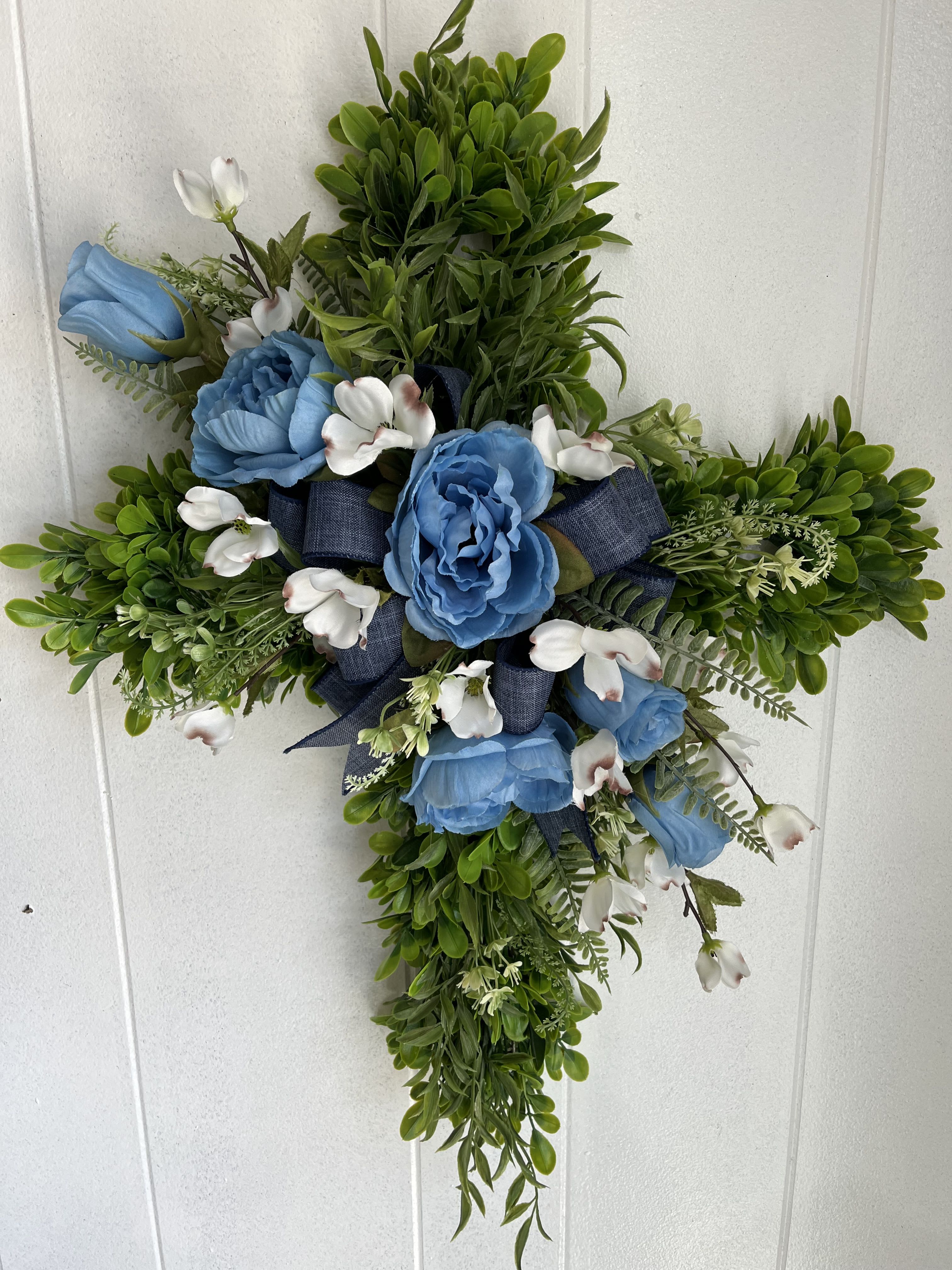 Cross-shaped floral arrangement with blue roses and white blossoms