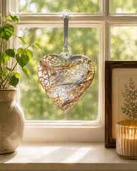 Heart-shaped glass ornament hanging in a sunlit window
