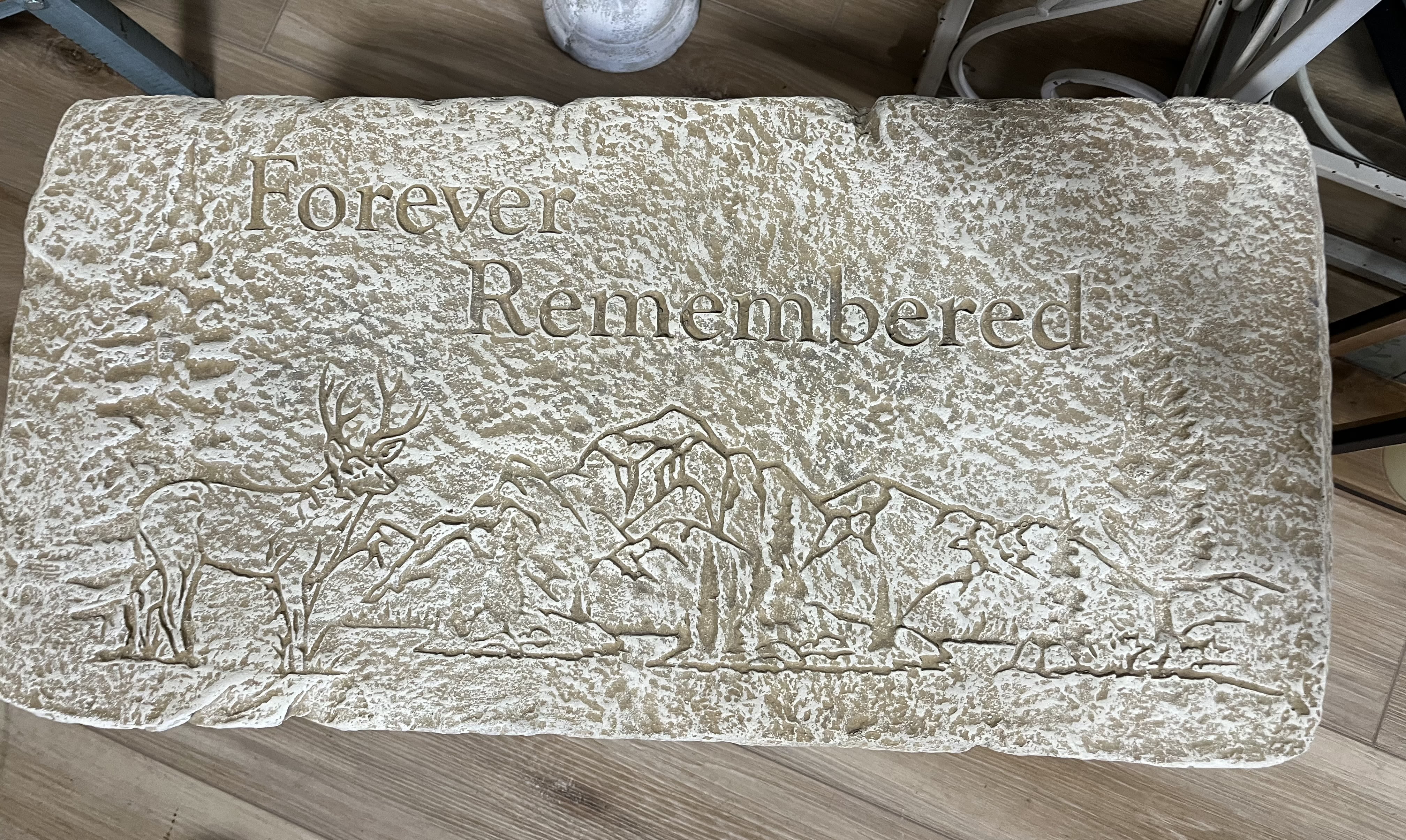 Rectangular memorial stone engraved with 'Forever Remembered' and a deer and mountain scene.