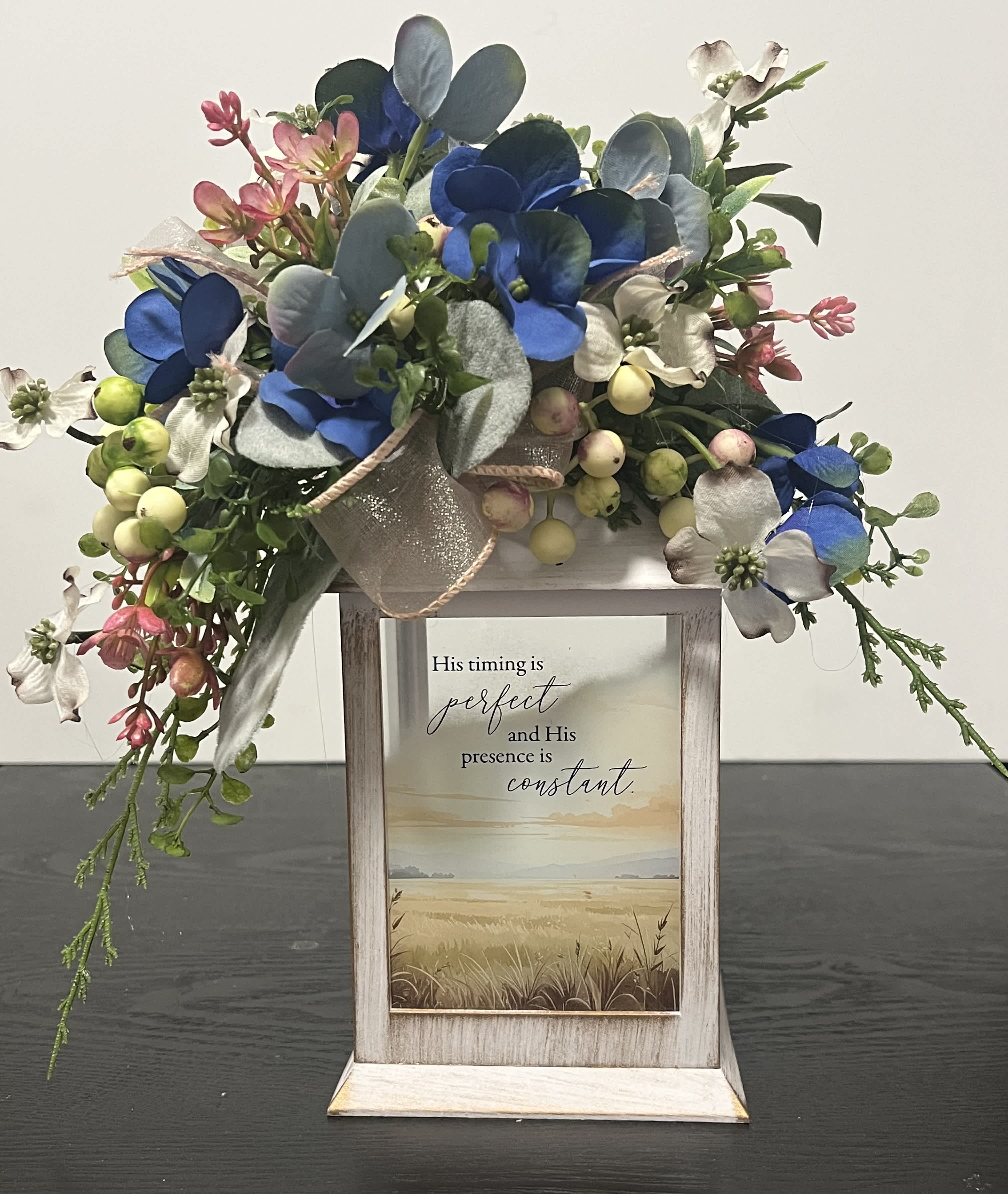 Floral arrangement with blue and white blooms in a rustic wooden frame sign