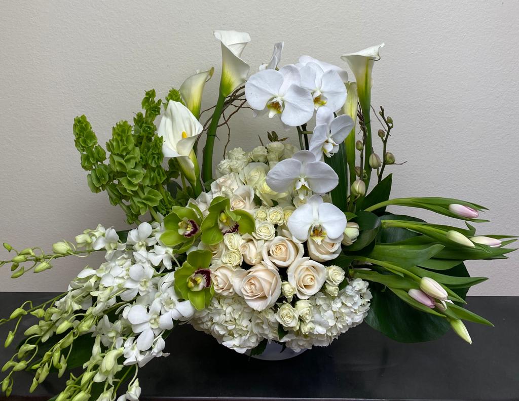 White orchids, calla lilies, roses, and green blooms in a low arrangement
