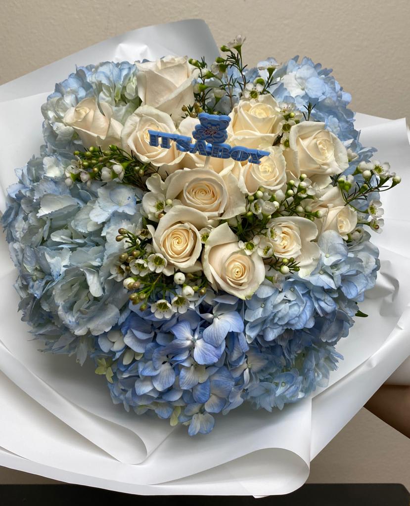Blue hydrangea bouquet with white roses and a baby boy topper