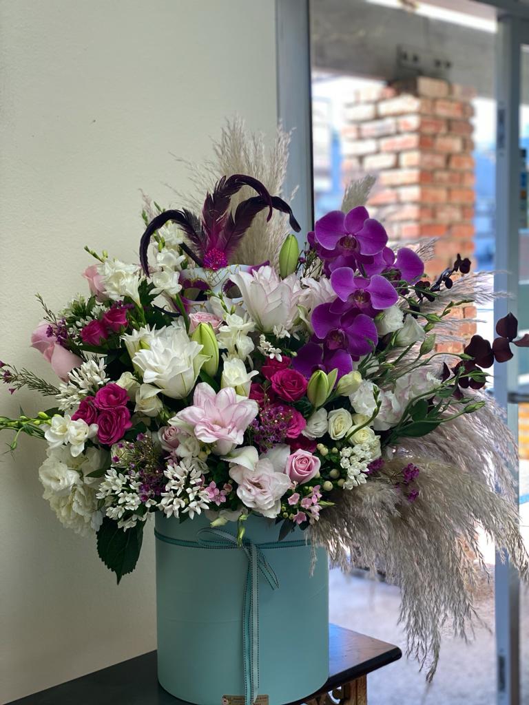 Large bouquet of pink, white, and purple flowers in a blue hat box