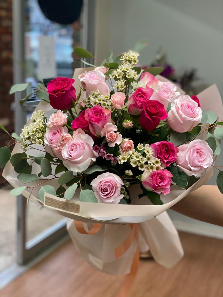 Bouquet of pink and red roses wrapped in cream paper