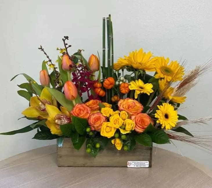 Mixed bouquet with yellow daisies, orange roses, and tulips in a wooden box