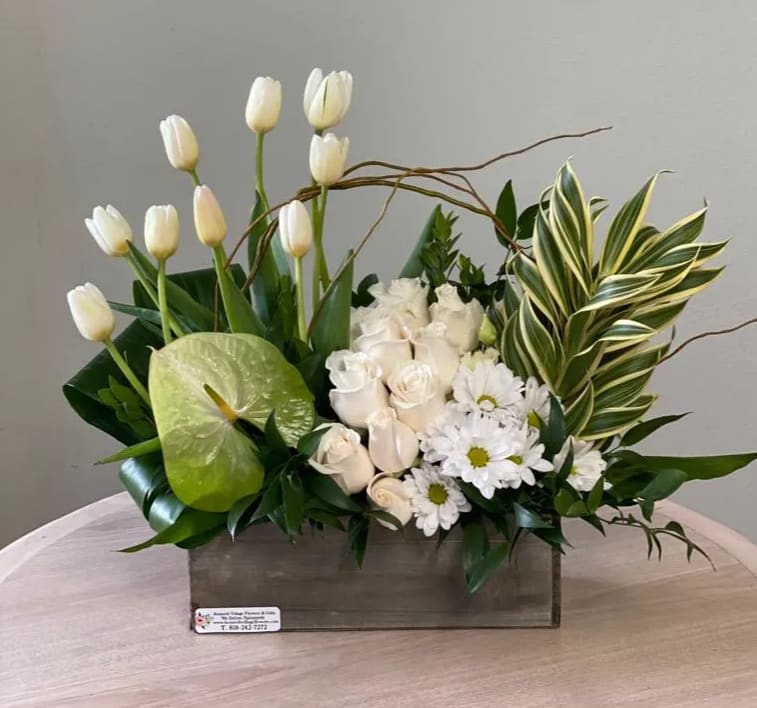 White tulips, roses, and daisies arranged in a wooden box