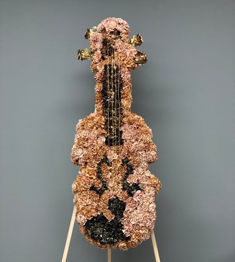 Floral arrangement shaped like a guitar on a stand