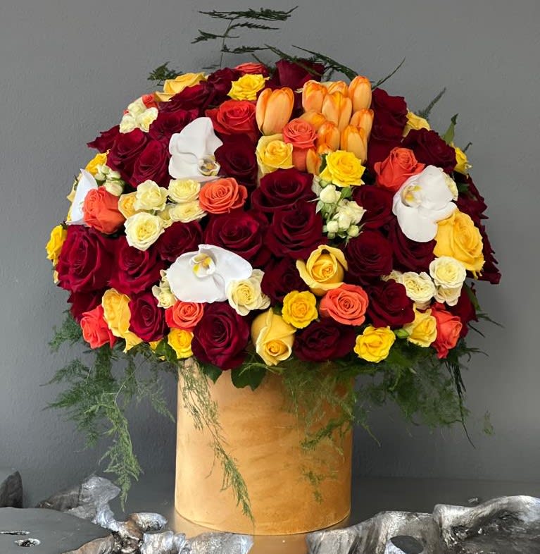 Large bouquet of red, yellow, orange, and white roses in a gold box