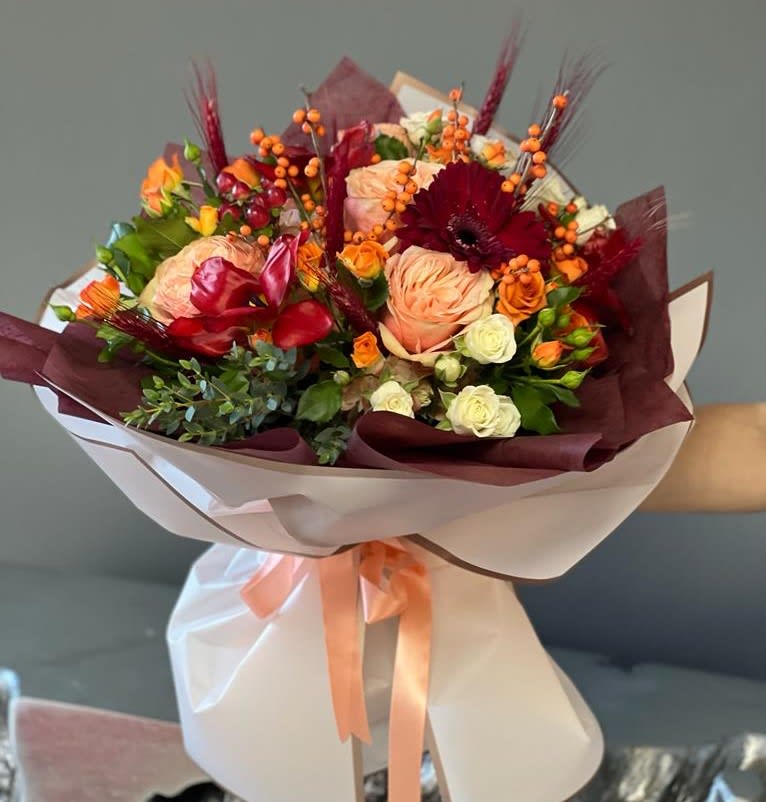 Bouquet of peach, red, and white roses with orange berries