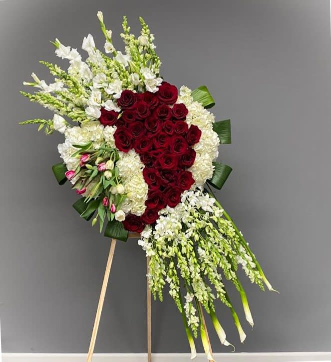 Standing floral spray with red roses and white flowers on an easel