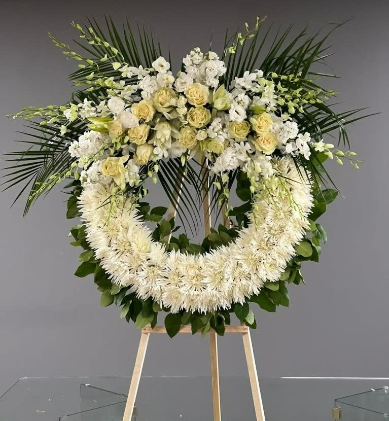 Large white floral wreath on a wooden stand
