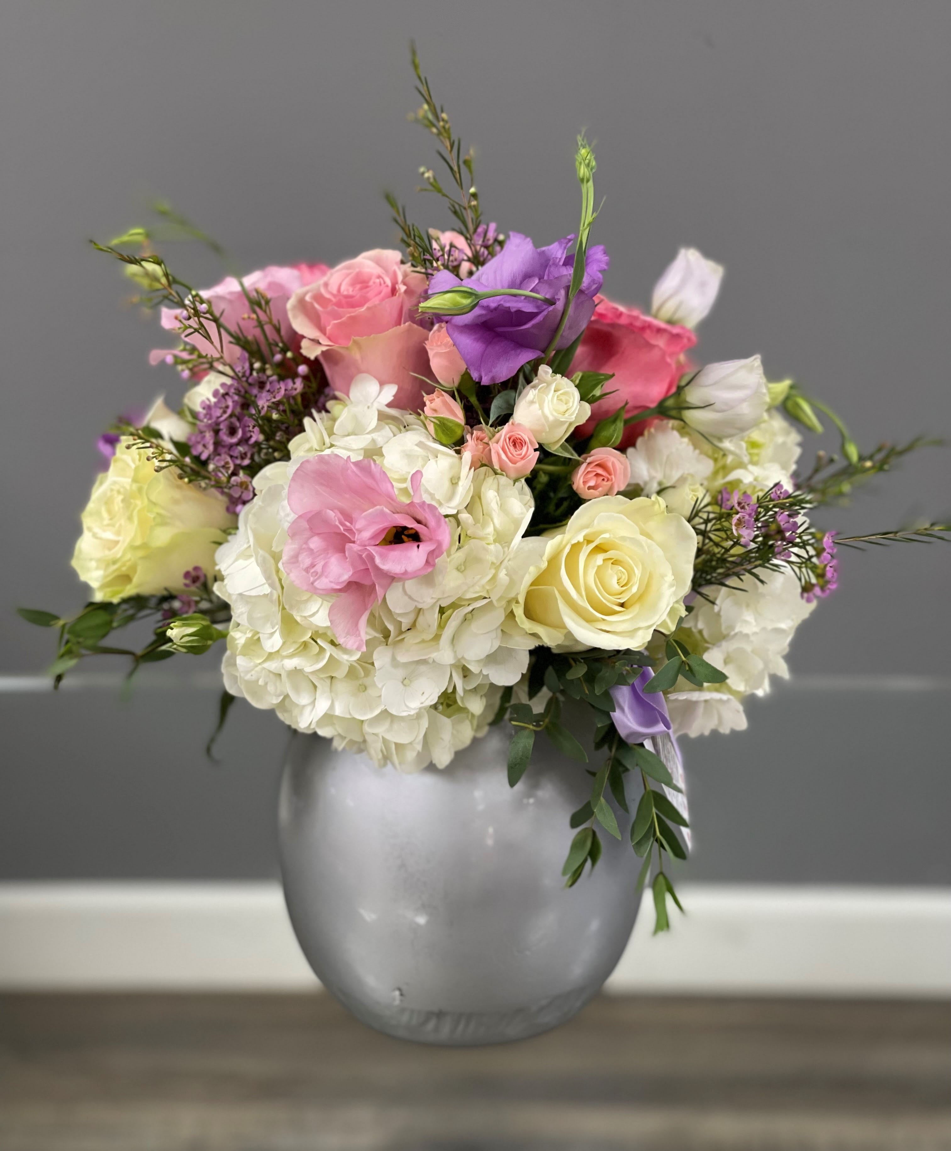 Mixed pink, white, and purple flowers arranged in a silver vase