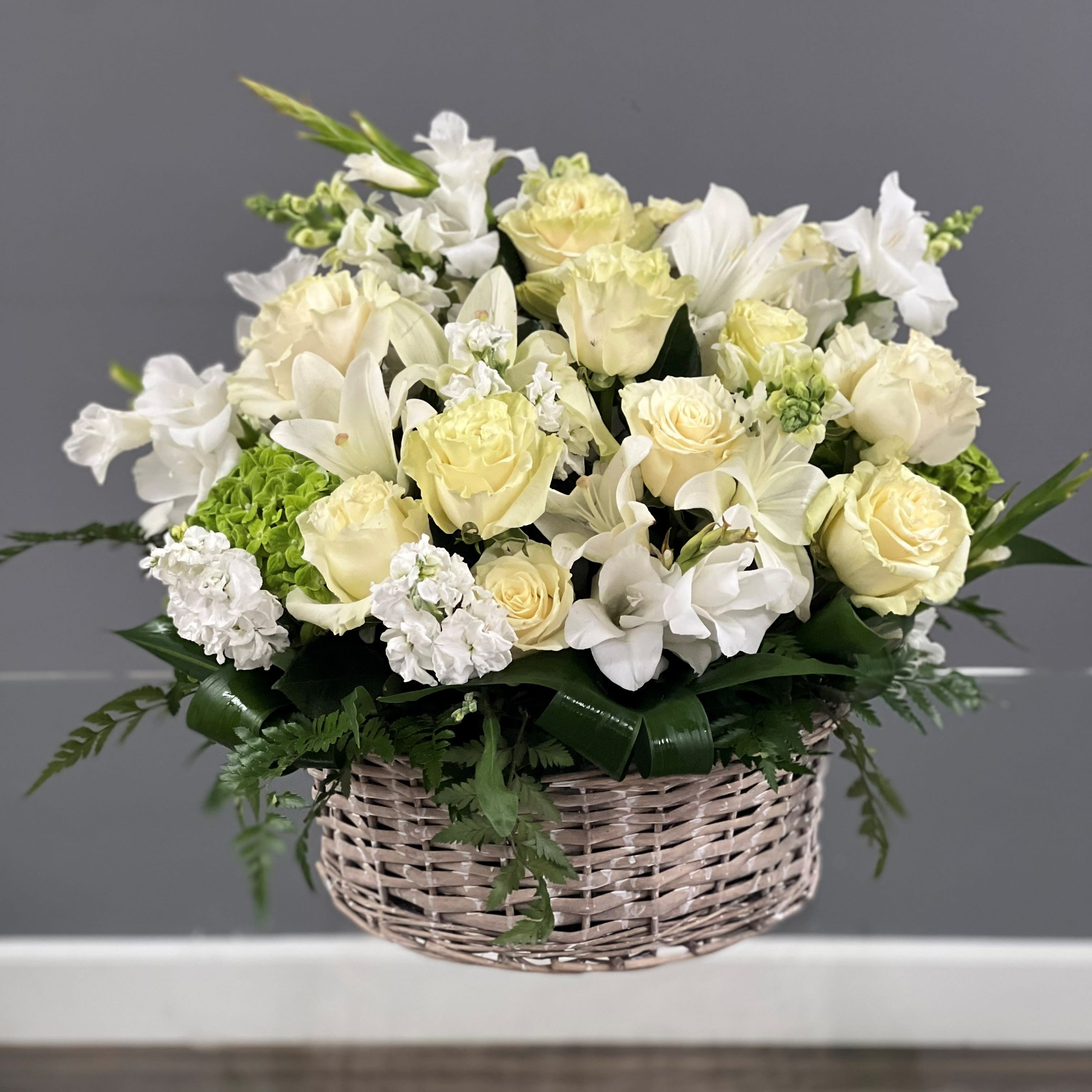 White and cream floral arrangement in a wicker basket